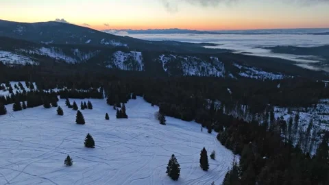 Aerial winter orbit over mountain meadow with ski tracks before sunrise Stock Footage 336445983