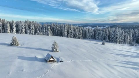 Aerial winter orbit of snow covered wooden cottage on mountain field Stock Footage 336384404