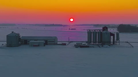 Aerial winter sunset over grain elevator rural Latvia snow covered landscape Stock Footage 330996917