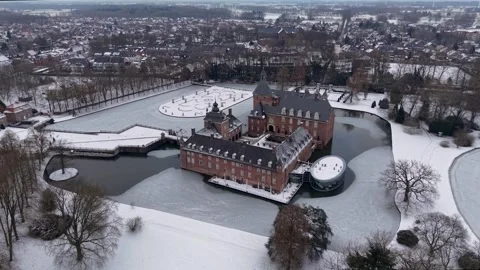 Aerial winter view of a red brick castle with towers and a moat beside a snow 스톡 동영상 329104268