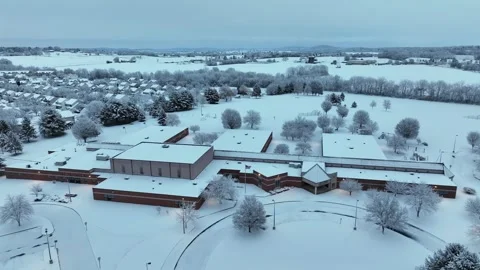 Aerial winter view of a snow-covered brick school building in an American Video stock 331665812
