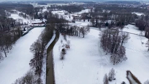 Aerial winter view of a winding river flowing through snowy fields and forests Stock Footage 329893259