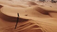 Aerial. Woman Weared In Long Dress Walking In The Dubai Desert Sand Dunes With Stock Footage