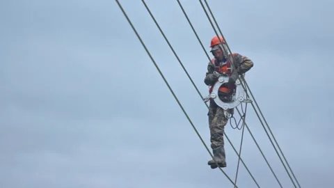 An aerial worker installs a separator for high-voltage wires while working at Stock-Footage 263539600
