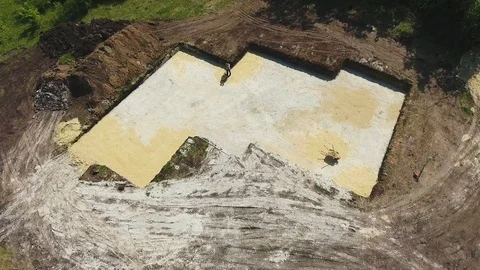 Aerial of worker with vibratory plate compactor ramming sand in foundation pit Stock Footage 110790639