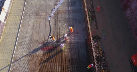 Aerial of workers pouring concrete in the metal grid while constructing a bridge Stock Footage