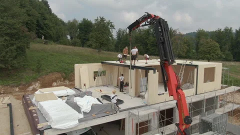 AERIAL: Workers use crane to place roof panel onto house under construction Stock Footage 307835775