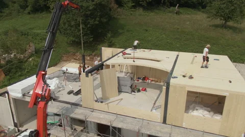 AERIAL: Workers use crane to place metal beam onto house under construction Stock Footage 307836249