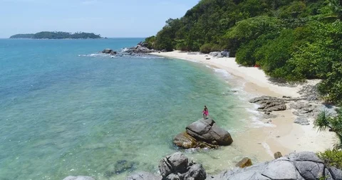 Aerial: Young beautiful model is dancing on top of a large stone on the beach. Stock Footage 87824905