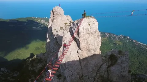 Aerial: Young Extreme Hiker Man Walking on a Suspension Bridge. Popular Russian Stock Footage