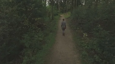Aerial of a young woman walking through a forest, low altitude tracking shot 動画素材 60065053