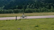 Aerial - Young Woman In A White Dress Riding Bicycle On A Rural Road Stock Footage