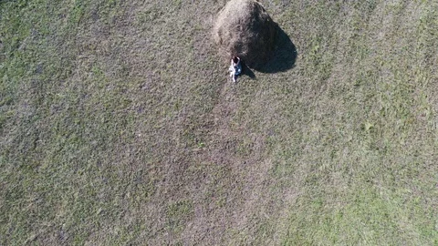 Aero flight over the field and haystack where the girl sits Stock Footage 128350852