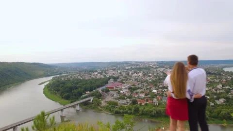Aero shot of couple standing on the top of the mountain above the city panorama Stock Footage 213625316