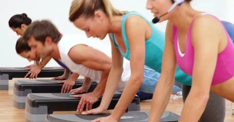 Aerobics class doing press ups together led by instructor Stock Footage 36398077