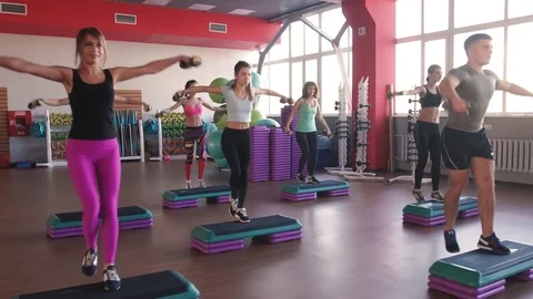 Aerobics class stepping and clapping together at the gym Stock-Footage 75869554
