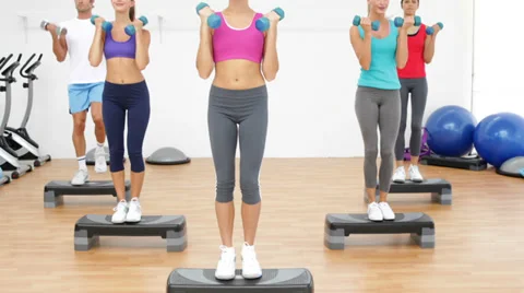 Aerobics class stepping together led by instructor and lifting dumbbells Stock Footage 36898963