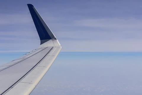 Aeroplane wing as seen from inside of flight through window. Clouds and blu.. Stock Photos