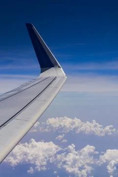 Aeroplane wing as seen from inside of flight through window. Clouds and blu.. Stock Photos