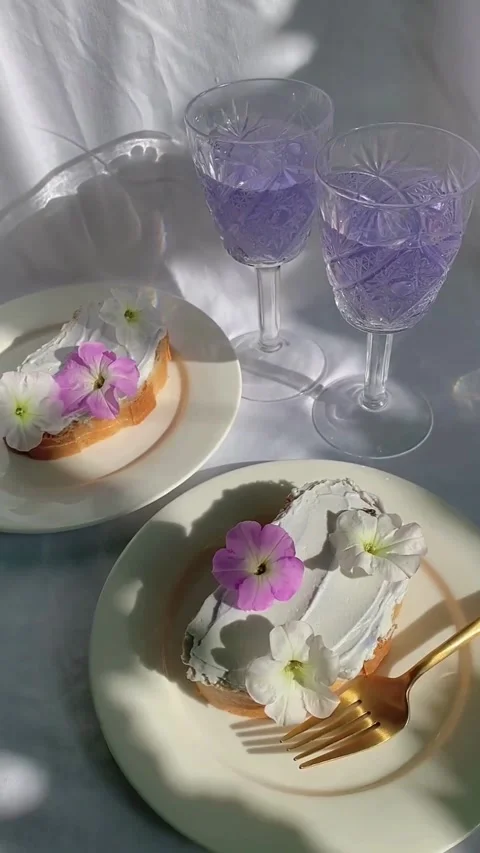 Aesthetic brunch table setting with floral toast and purple drinks Stock Footage 344016818