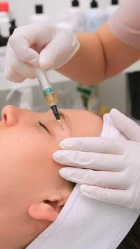 Aesthetic medicine professional administering a plasma injection into a fem.. Фото
