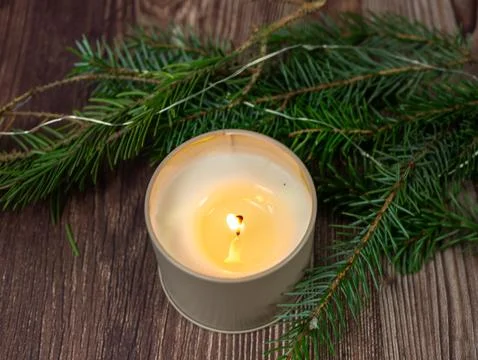 Aesthetic winter flat lay featuring burning candle surrounded by green pine.. Stock Photos