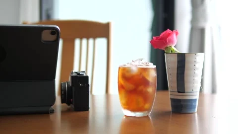 Aesthetic workspace with iced coffee, tablet, vintage camera, and pink rose Stock Footage 332421916