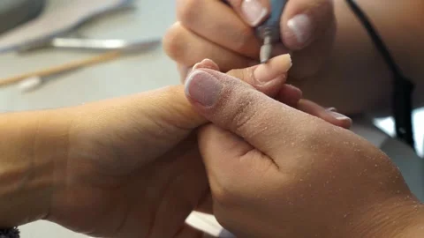 Aesthetician doing manicure by filing nails with an electric nail polisher at a Stock Footage 252135604