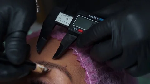 Aesthetician measuring the eyebrows of a client prior to starting micro Stock Footage 97389085