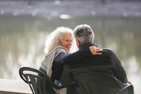 Affectionate active senior couple hugging at park pond Fotos de archivo