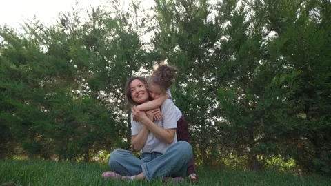 Affectionate Child Hugging Mother from Behind in a Garden Stock Footage 306732624