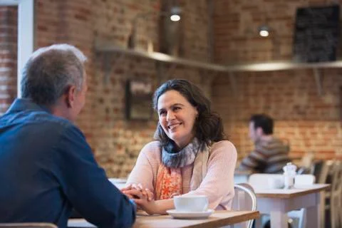 Affectionate couple holding hands talking in cafe Stock Photos