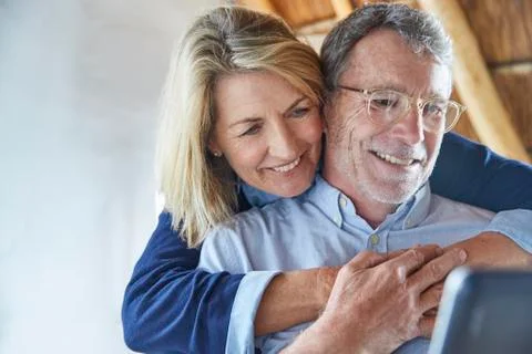 Affectionate couple hugging and using laptop Stock Photos