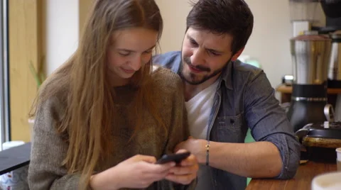 Affectionate couple looking at smartphone together in coffee shop Stock Footage 63301371