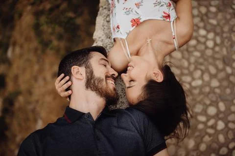 Affectionate couple resting while lying on stone fence in mountains Stock Photos