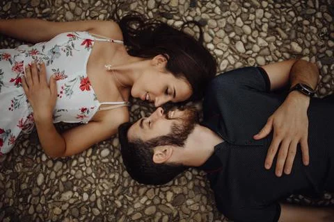 Affectionate couple resting while lying on stone fence in mountains Stock Photos