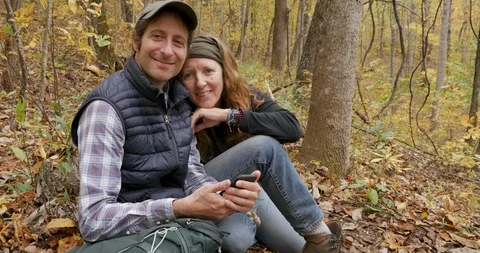 Affectionate couple sitting in the forest smiling and looking at the camera Stock Footage 112019825
