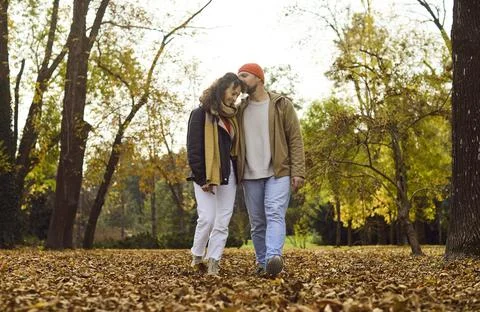 Affectionate couple strolling in fall park, cuddling amid warm colors and leaves Fotos Stock