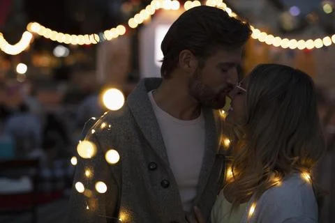 Affectionate couple wrapped in string lights Stock Photos