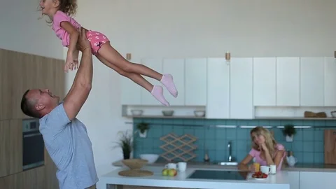 Affectionate dad raising daughter up in the kitchen Video stock 79747464