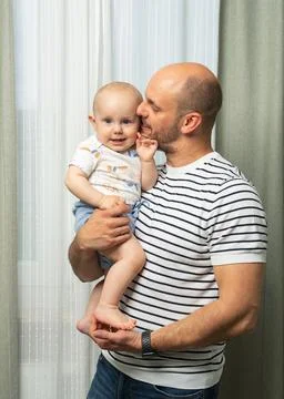 Affectionate father with a beard gently holding his toddler in candid and emo Stock Photos