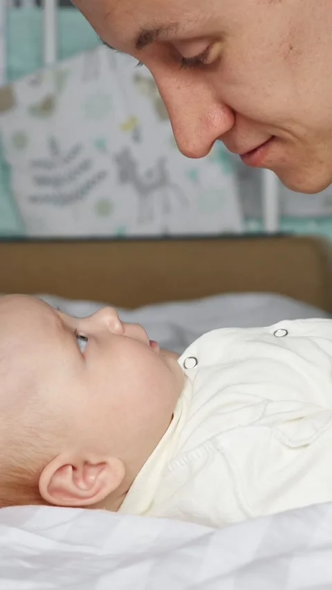 Affectionate father communicating with his newborn son lying in a crib Stock-Footage 341285716