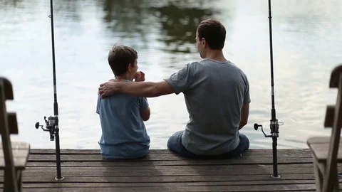 Affectionate father embracing son as they fish Video stock 78572834