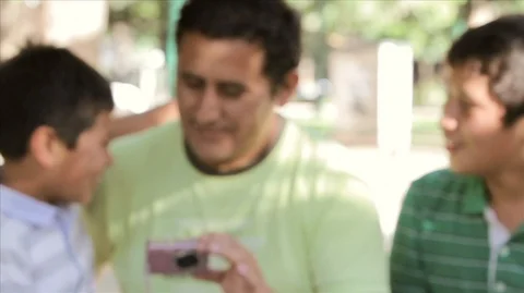 Affectionate father showing something on a digital camera to his two sons. 스톡 동영상 88406960