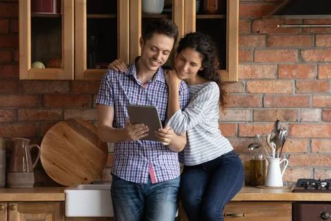 Affectionate happy young family couple using digital touchpad gadget. Stock Photos
