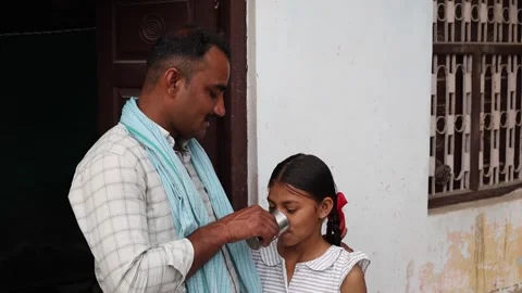 Affectionate Indian father helping young daughter drink water or milk from .. Vídeo Stock 335119439