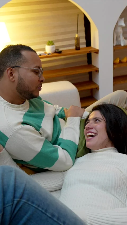 Affectionate interracial couple sharing a tender moment on the couch Stock Footage 334134259