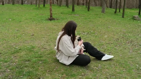 Affectionate long-haired woman sitting on the green grass, gently holding and Stock-Footage 342951495