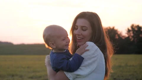 Affectionate mother holding happy son at sunset Vidéo 332777336