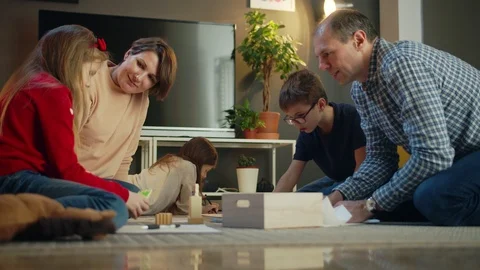 Affectionate parents and nice pretty children playing with wooden blocks at cozy Stock Footage 125903610